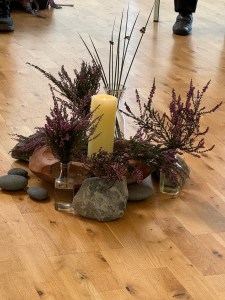 Pillar candle surrounded by stones and vases of heather