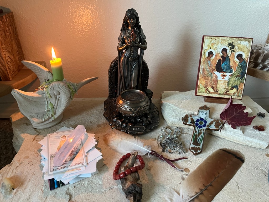 Altar with statue of Brigid, icon of the Holy Trinity, and lit candle
