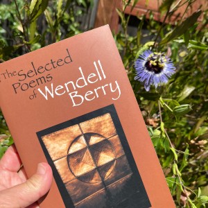Photo of book The Selected Poems of Wendell Berry next to a passionflower